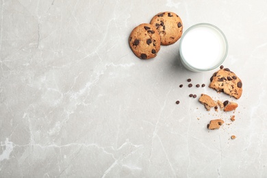 Flat lay composition with chocolate cookies and glass of milk on gray background. Space for text