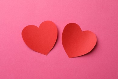 Red paper hearts on pink background, flat lay