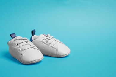 Cute baby shoes on light blue background, space for text