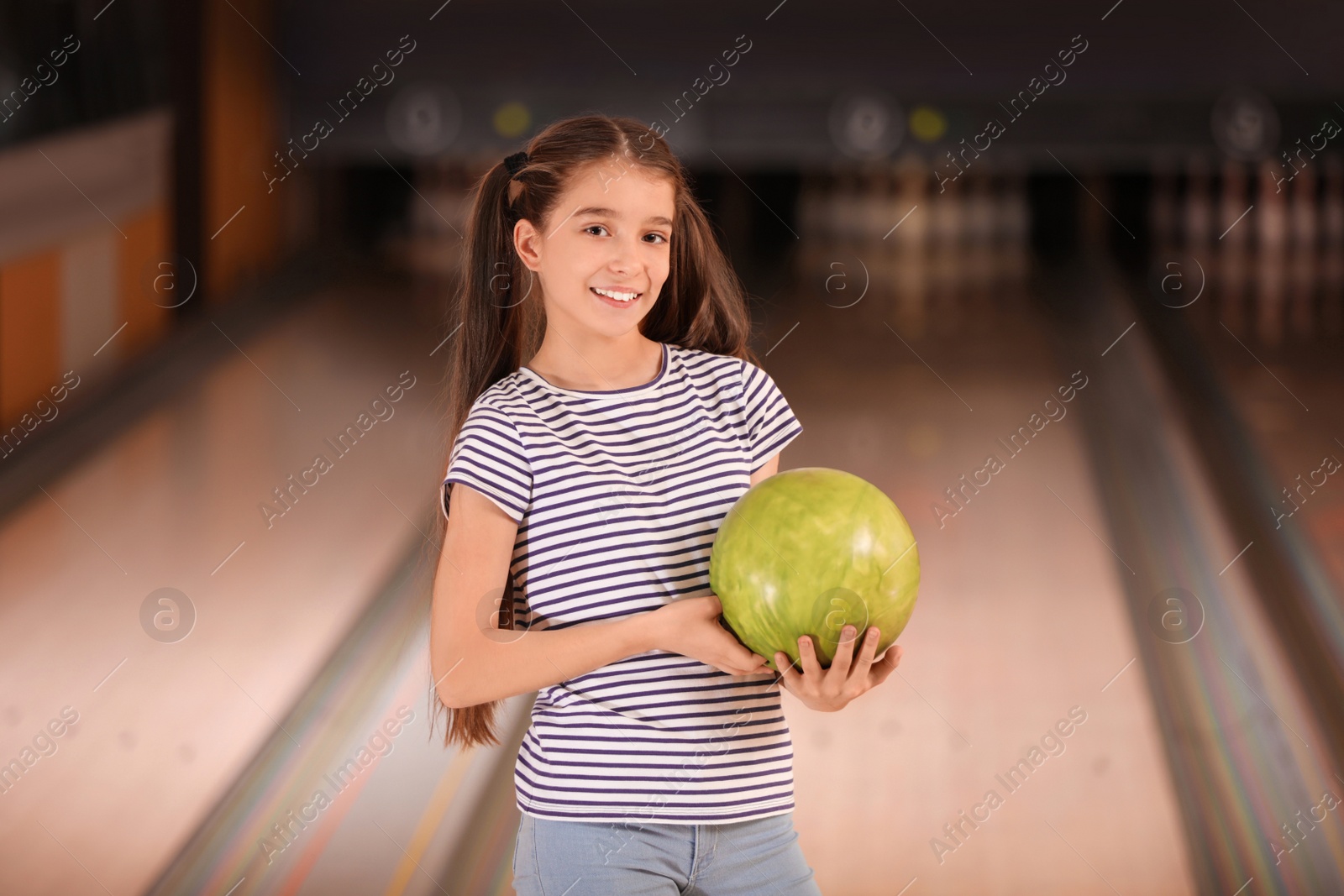 Photo of Preteen girl with ball in bowling club