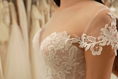 Photo of Woman trying on wedding dress in boutique, closeup