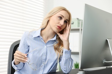 Overwhelmed woman with glasses at table in office