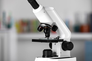 Modern medical microscope with glass slide on blurred background, closeup