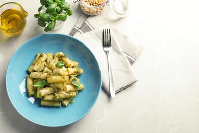 Photo of Flat lay composition with plate of delicious basil pesto pasta and space for text on gray table