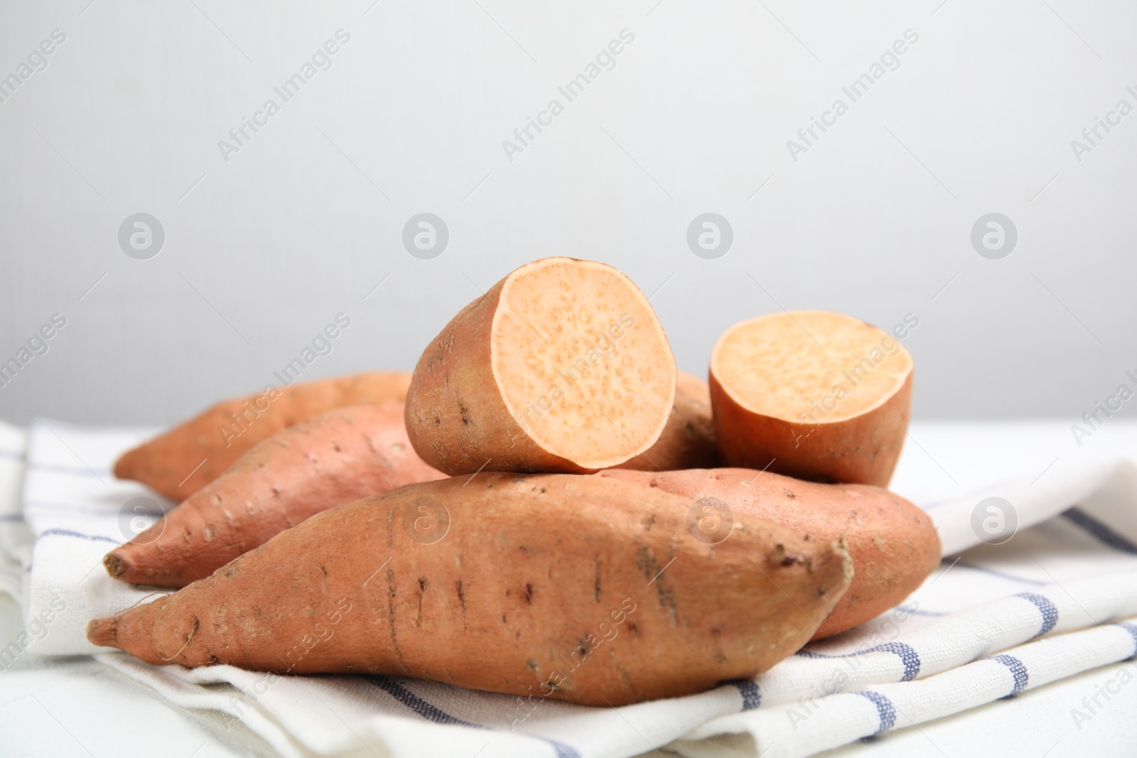 Photo of Whole and cut ripe sweet potatoes on kitchen towel