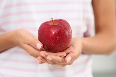 Photo of Woman holding fresh red apple indoors, closeup