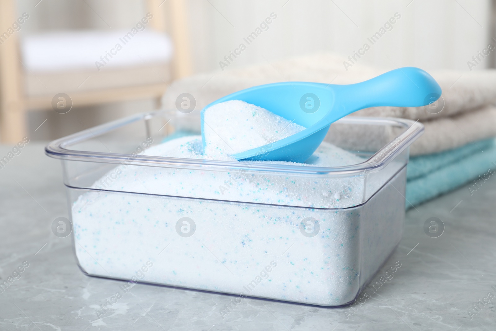 Photo of Container with laundry powder and measuring scoop on table