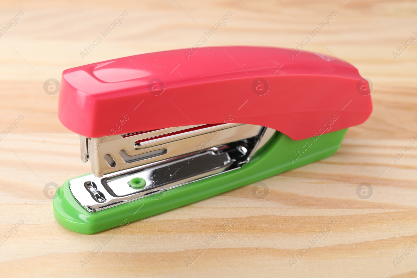Photo of One bright stapler on wooden table, closeup