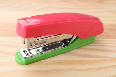 Photo of One bright stapler on wooden table, closeup