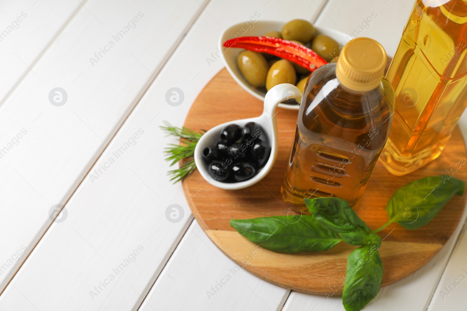 Photo of Different cooking oils and ingredients on white wooden table, space for text