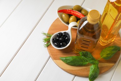 Different cooking oils and ingredients on white wooden table, space for text