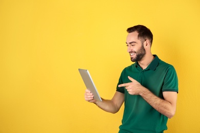 Photo of Man using tablet for video chat on color background. Space for text