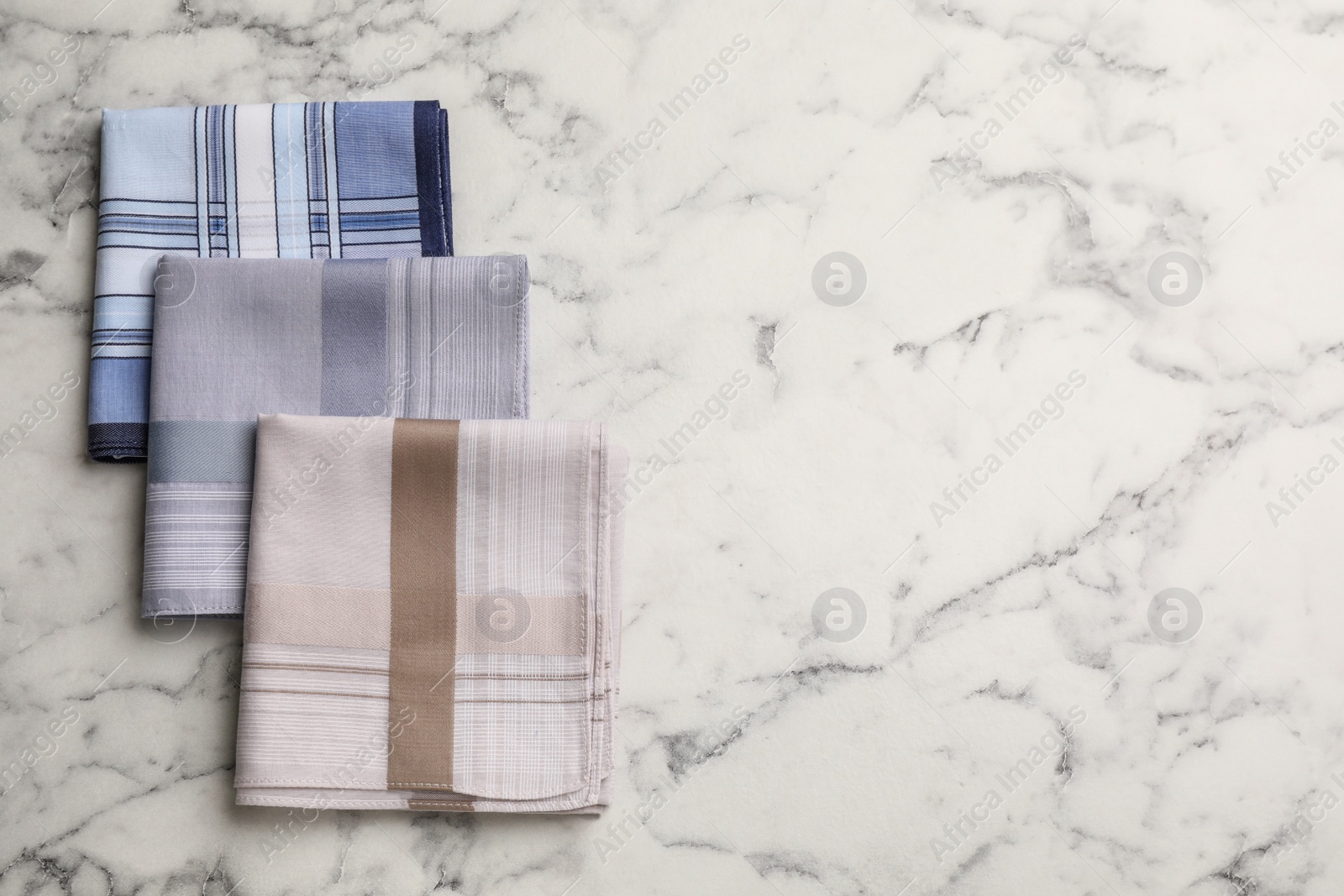 Photo of Different handkerchiefs folded on white marble table, flat lay. Space for text