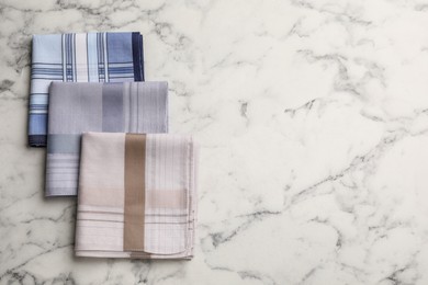 Different handkerchiefs folded on white marble table, flat lay. Space for text