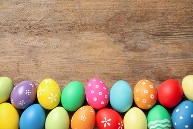 Photo of Colorful Easter eggs on wooden background, flat lay. Space for text