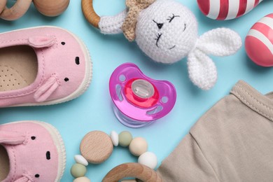 Flat lay composition with pacifier and other baby stuff on light blue background