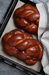 Photo of Homemade braided bread on grey table, top view. Traditional challah