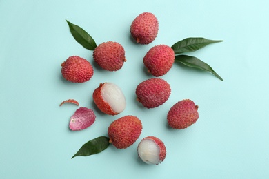 Fresh ripe lychees with leaves on turquoise background, flat lay