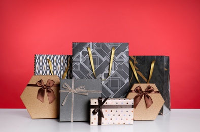 Photo of Shopping paper bags and gift boxes on red background