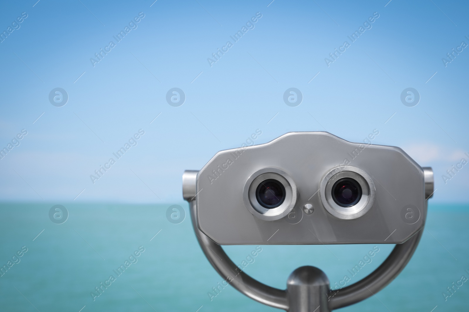 Photo of Metal tower viewer installed near sea. Mounted binoculars