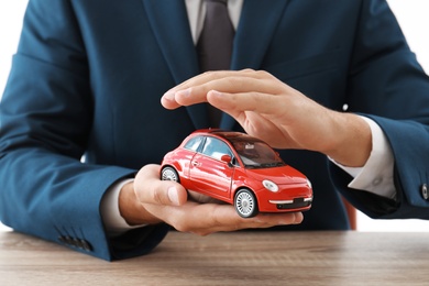 Insurance agent holding toy car over table, focus on hands