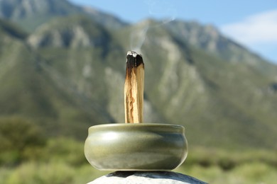 Photo of Burning palo santo stick in high mountains, closeup