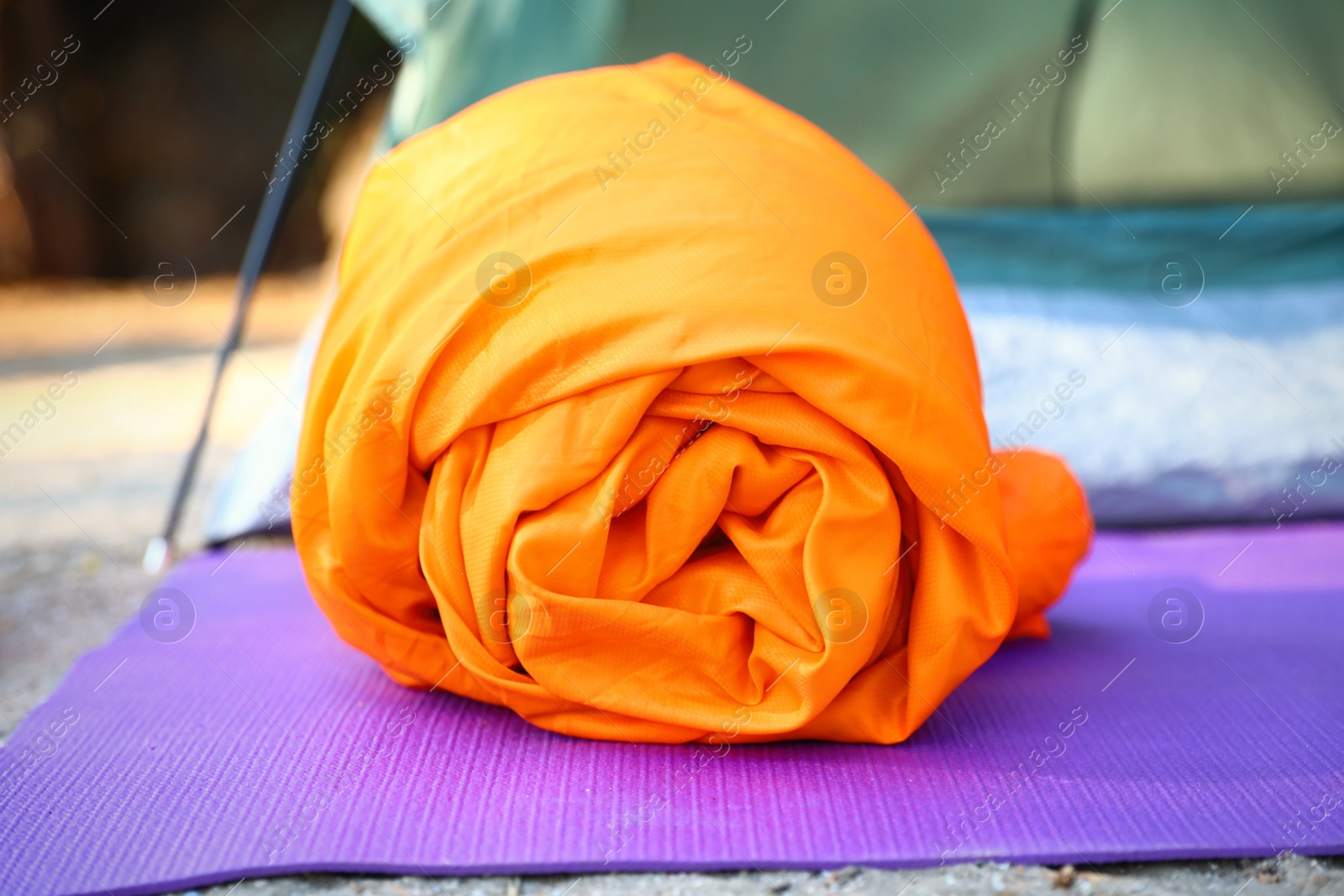 Photo of Rolled sleeping bag on mat outdoors, closeup