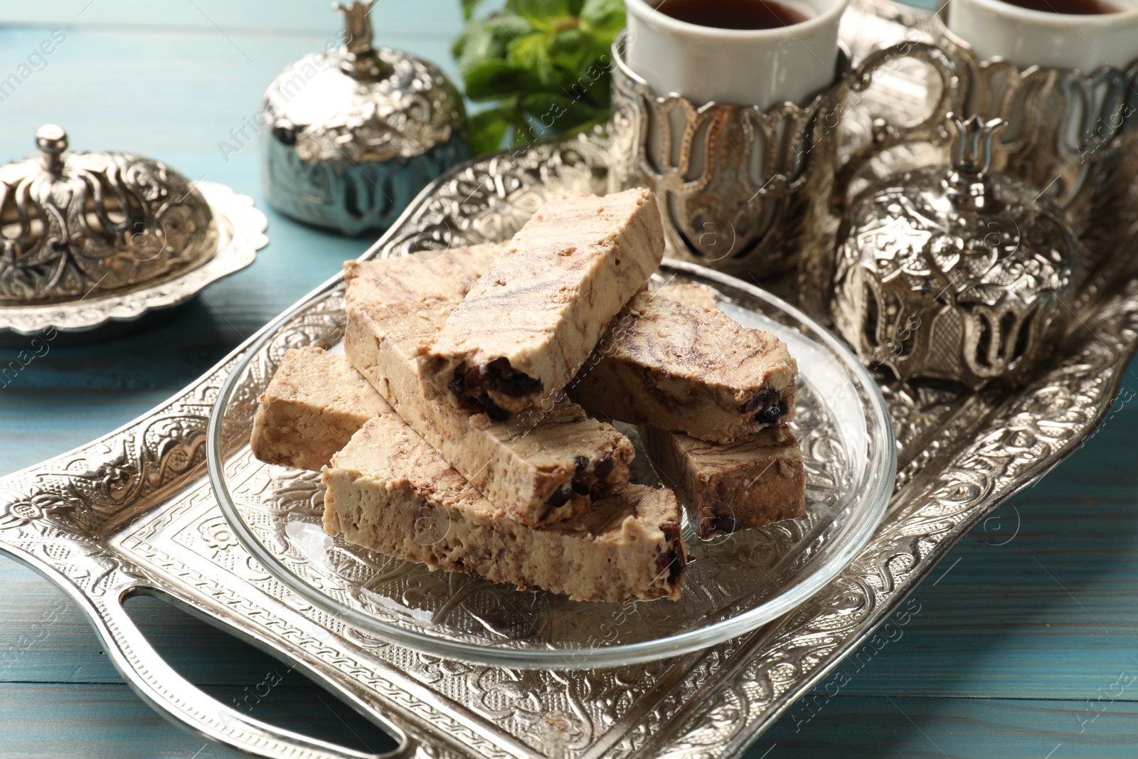 Photo of Tasty chocolate halva served on light blue wooden table