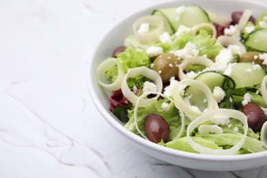 Bowl of tasty salad with leek, olives and cheese on white textured table, closeup. Space for text