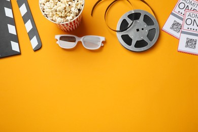 Flat lay composition with popcorn and film reel on orange background, space for text