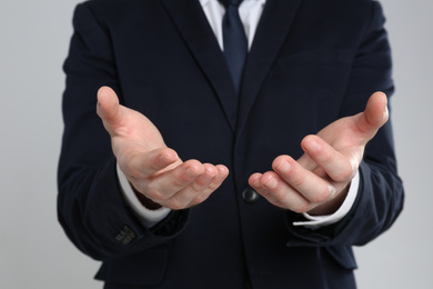 Photo of Businessman holding something against grey background, focus on hands