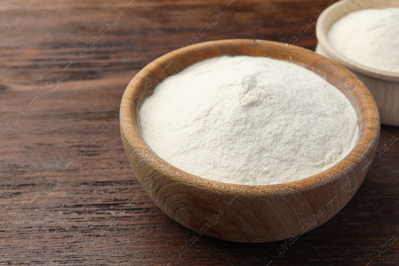 Photo of Bowls of agar-agar powder on wooden table, closeup. Space for text