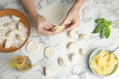 Woman cooking dumplings over marble table, top view