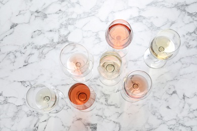 Different glasses with wine on marble background, flat lay