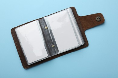 Photo of Leather business card holder with blank cards on light blue background, top view