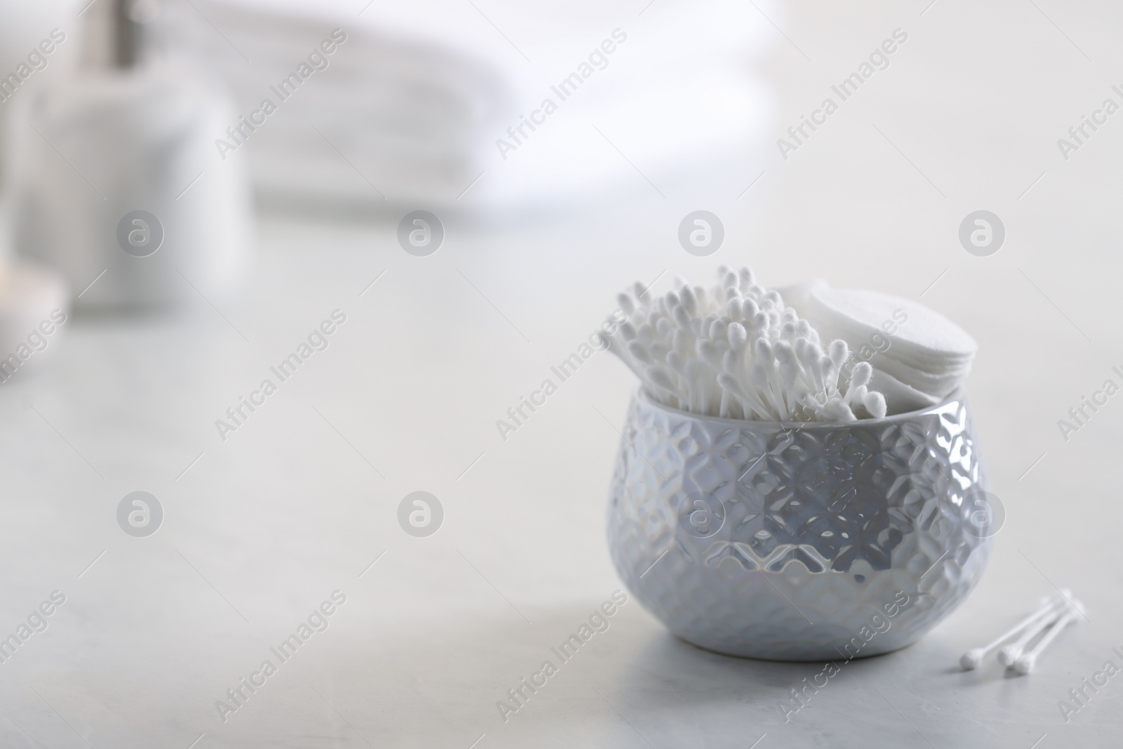 Photo of Cotton buds in holder on white table indoors, space for text