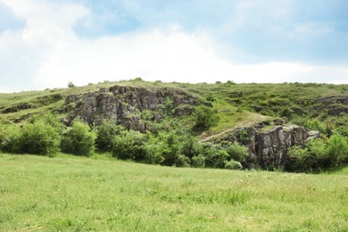 Picturesque landscape with rocky hill and green plants. Camping season
