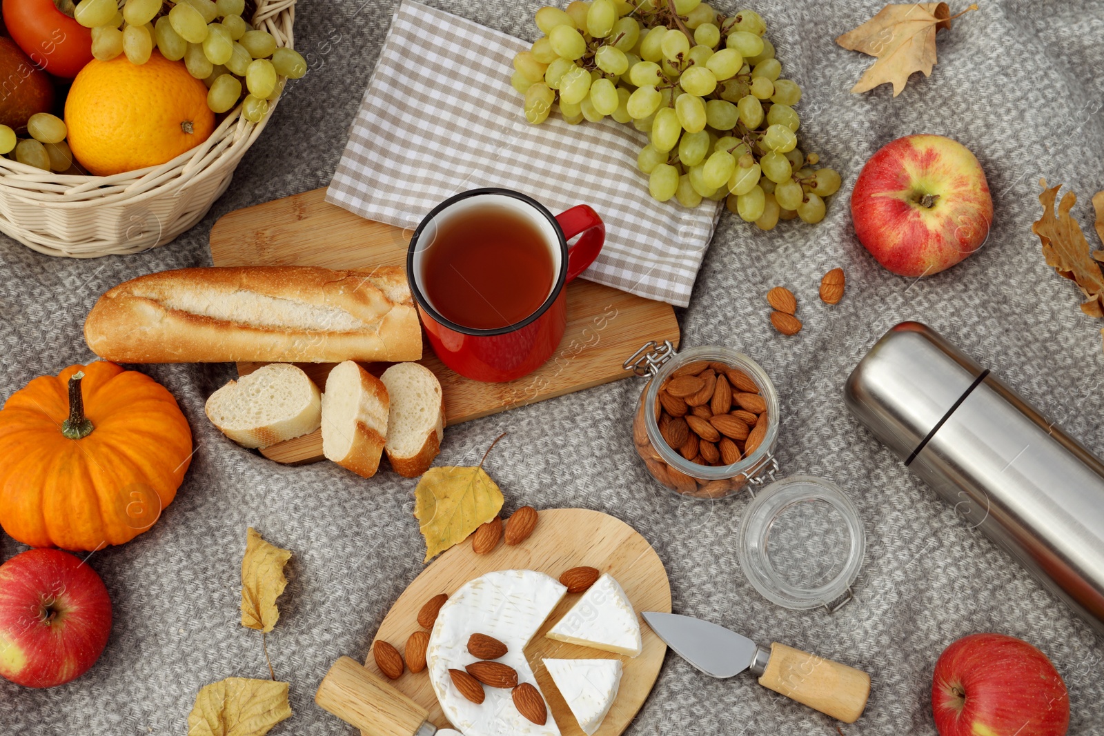 Photo of Blanket with picnic basket, snacks and autumn leaves, flat lay