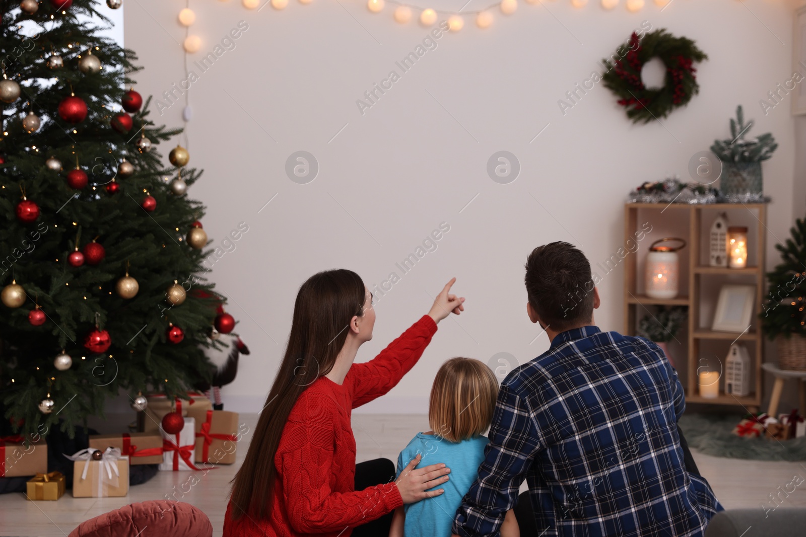 Photo of Family watching Christmas movie via projector in cosy room, back view. Winter holidays atmosphere