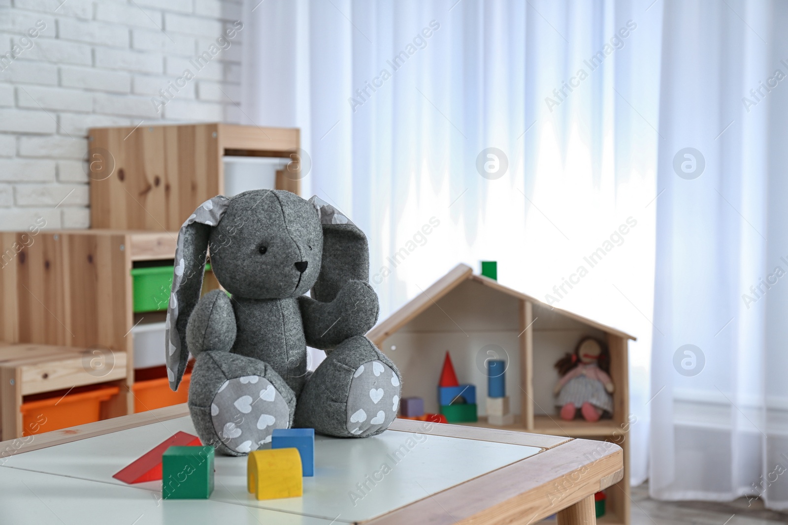 Photo of Stuffed rabbit on table in child room interior