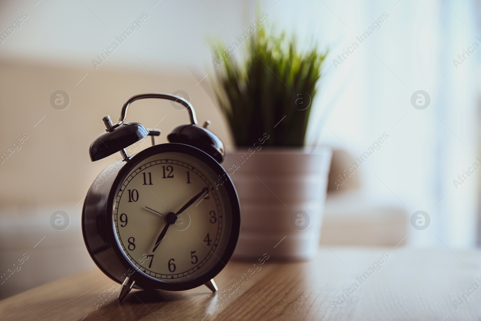 Photo of Alarm clock on wooden table at home. Morning time