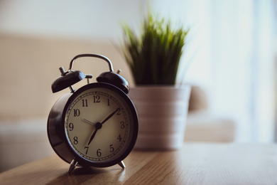 Alarm clock on wooden table at home. Morning time