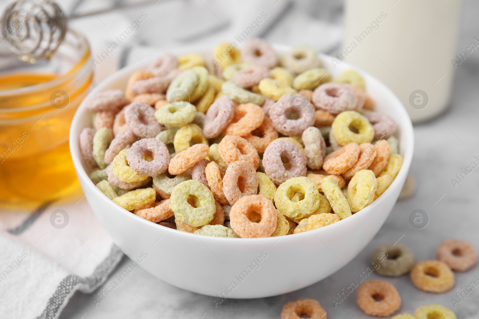 Photo of Tasty cereal rings in bowl on light table, closeup