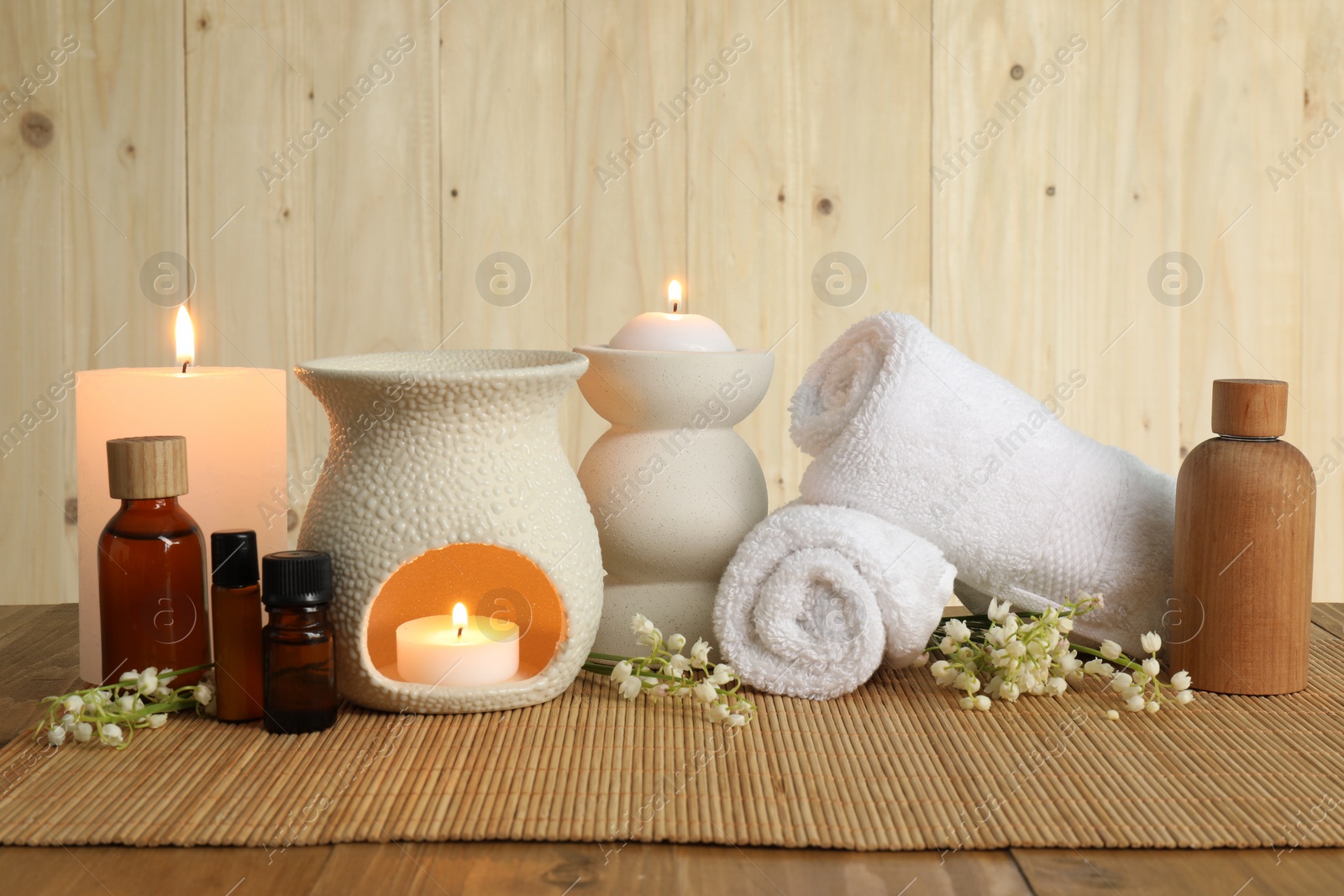 Photo of Aromatherapy. Scented candles, bottles, flowers and towels on wooden table