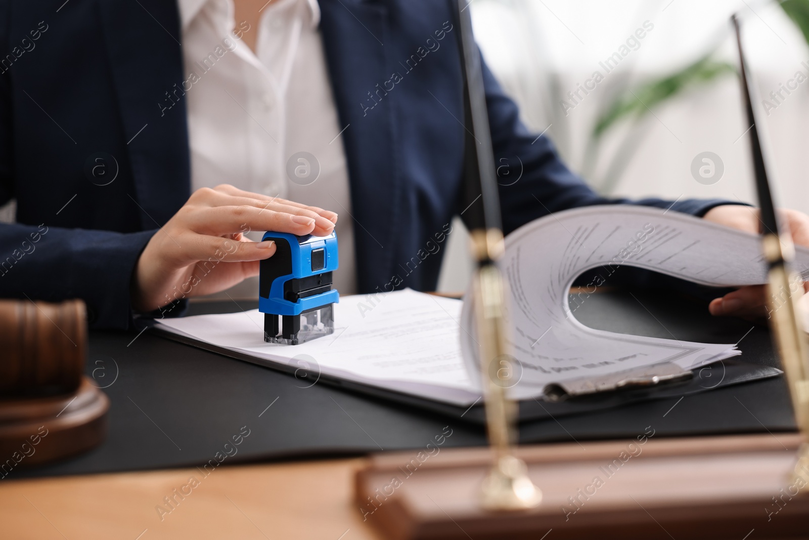 Photo of Notary stamping document at table in office, closeup