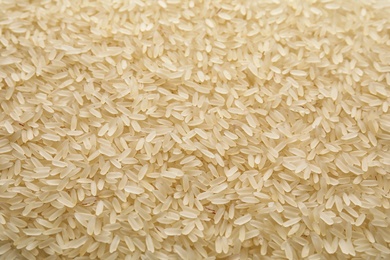 Photo of Pile of uncooked rice as background, closeup