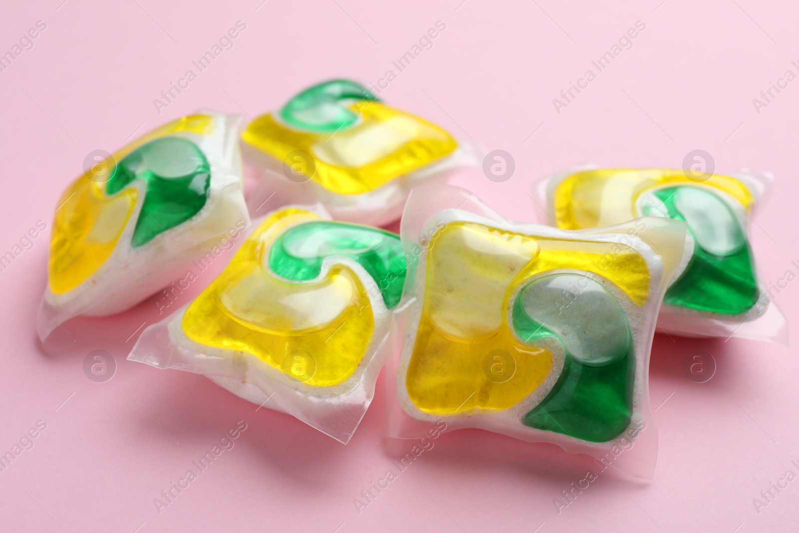 Photo of Many dishwasher detergent pods on pink background