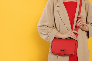 Photo of Woman with stylish bag on yellow background, closeup. Space for text