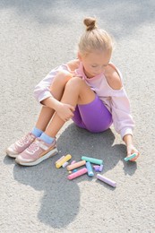 Photo of Little child drawing flower with chalk on asphalt