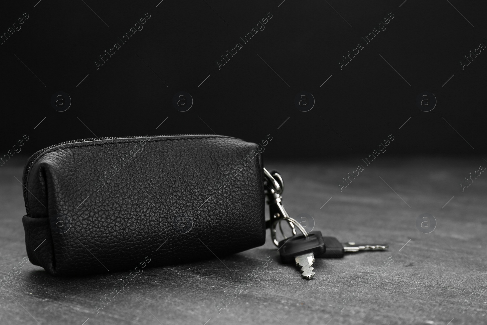 Photo of Leather case with keys on grey table, closeup. Space for text